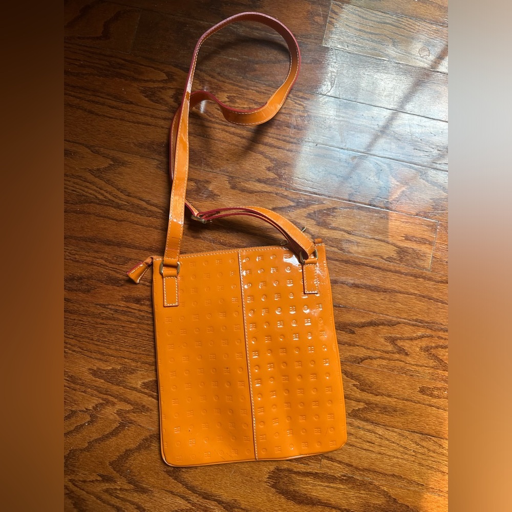 Arcadia monogram embossed patent leather crossbody bag in a vibrant orange hue.